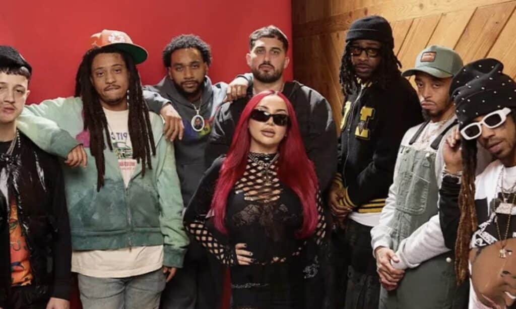 Lil WayneがYoung Money Radioに登場し、新世代のYoung Moneyアーティストを紹介している様子。赤い背景の前でマイクに向かって話している。