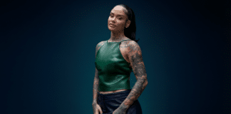 耳を潤す極上のR&Bに浸ろう:Kehlaniの新アルバム『Kehlani』レビュー Kehlaniのポートレート。エメラルドグリーンのレザートップスとネイビースカートを着用し、ミッドナイトブルーの背景の前でポーズを取る。両腕から首元にかけてフルスリーブタトゥー、スリックバックのポニーテール、ゴールドリングを複数着用。HIPHOPCs記事用ビジュアル。