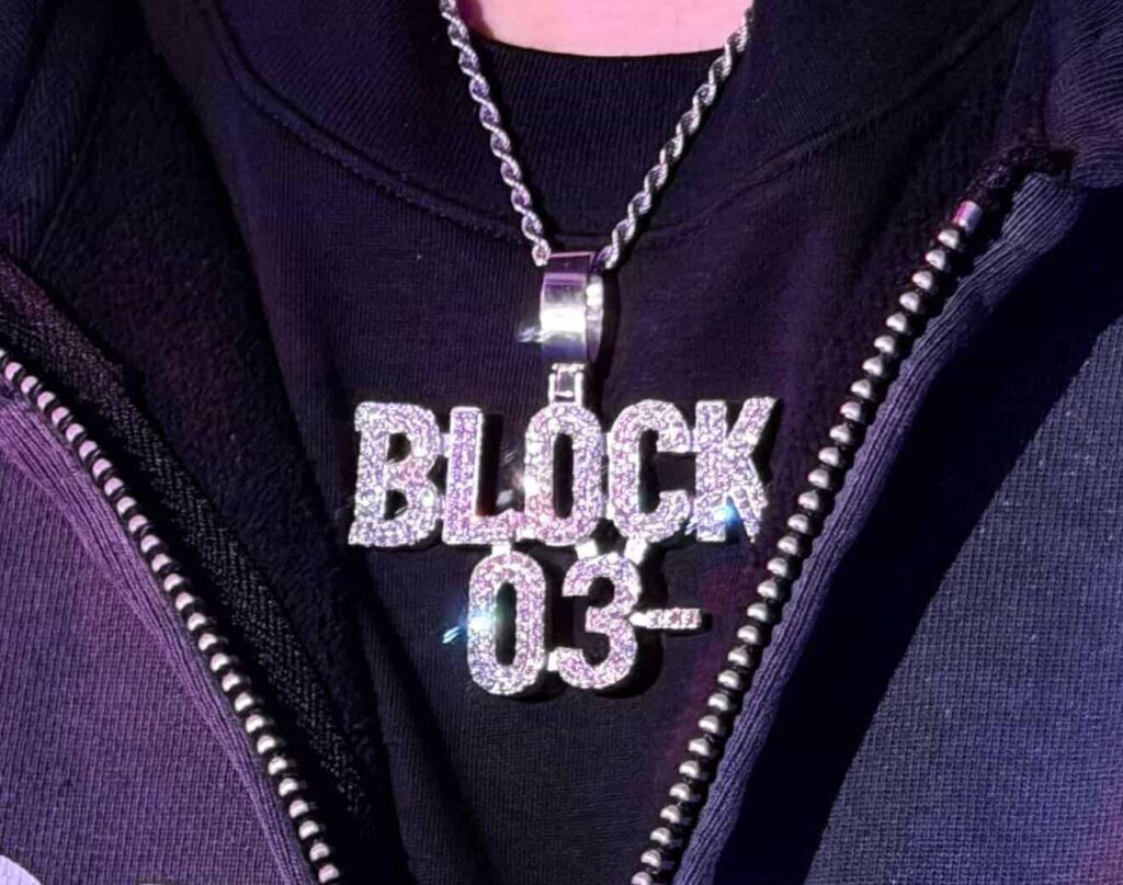 Rommy Montana が首から下げる「BLOCK 03-」ダイヤモンド・ペンダント。03- Performance のブランドロゴが立体化されたチェーン