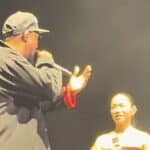 Kアリーナ横浜のステージ上で、RZAの隣に立つAWICHがマイクを持ち、英語MCを日本語に通訳する場面。Wu-Tang Clanの29年ぶり日本公演で、最後の邂逅と新しい共作の始まりを象徴した一幕。
