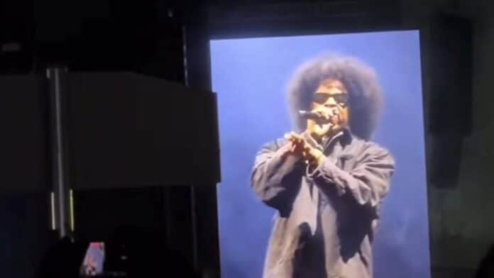 Roots Picnic 2026の会場スクリーンに映る、アフロとサングラス姿でマイクを握りフリースタイルを披露するJay-Z