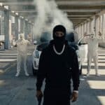 Tory Lanez『MADE YOU THINK I WAS GONE …BUT』のプロモーションビジュアルより、立体駐車場で黒いバラクラバ姿の人物を武装した集団が取り囲むシーン