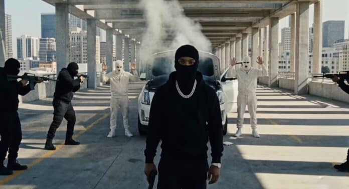 Tory Lanez『MADE YOU THINK I WAS GONE …BUT』のプロモーションビジュアルより、立体駐車場で黒いバラクラバ姿の人物を武装した集団が取り囲むシーン