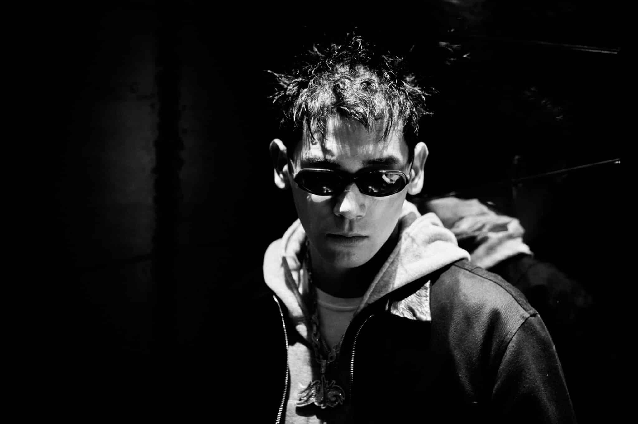 JIRO wearing sunglasses in a dark monochrome portrait