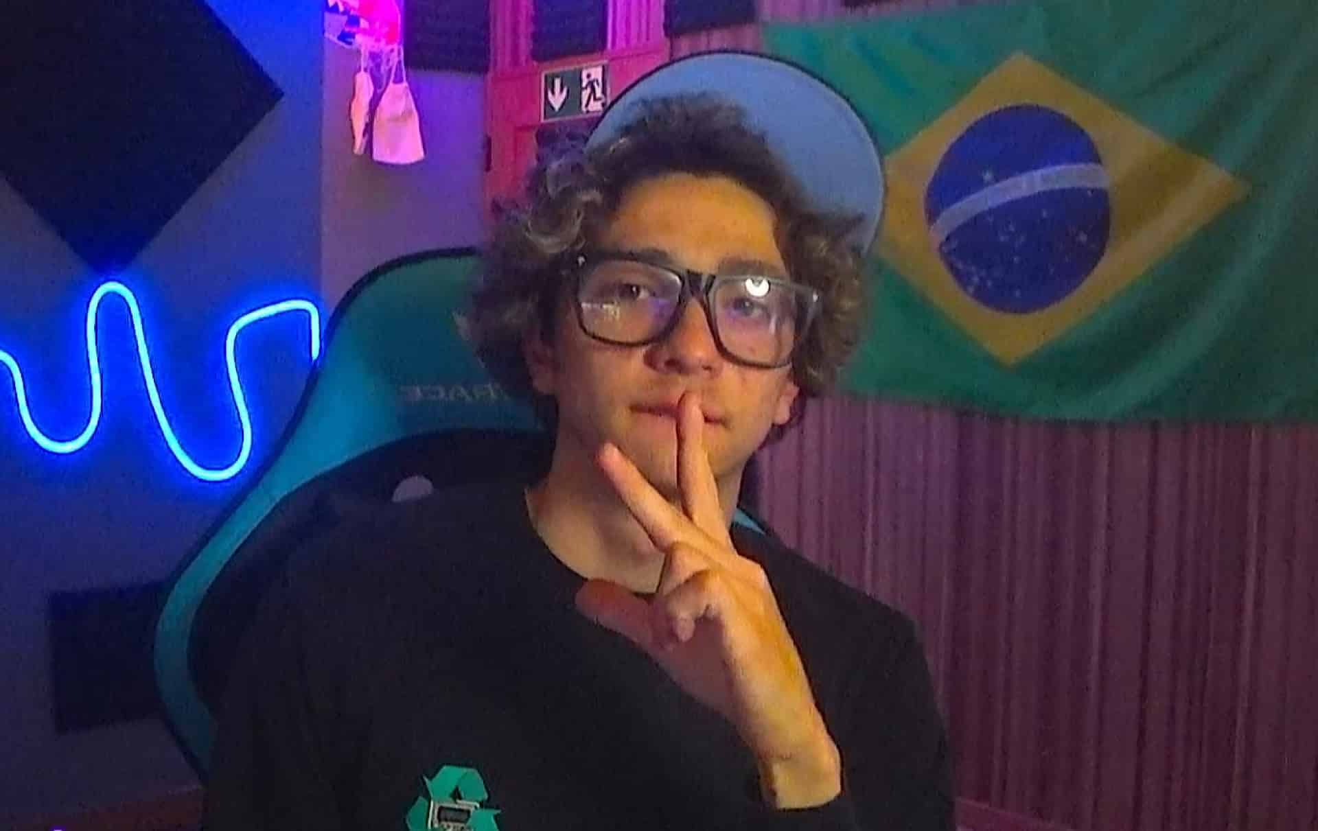 dominguap wearing glasses and a cap in a colorful room with a Brazilian flag behind him