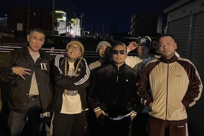 夜の屋外で5人のアーティスト仲間と並ぶ田中雄士