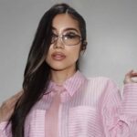 ピンクのストライプシャツとネクタイを着用し、白いヘッドホンを手にしたDJ Yukoのポートレート